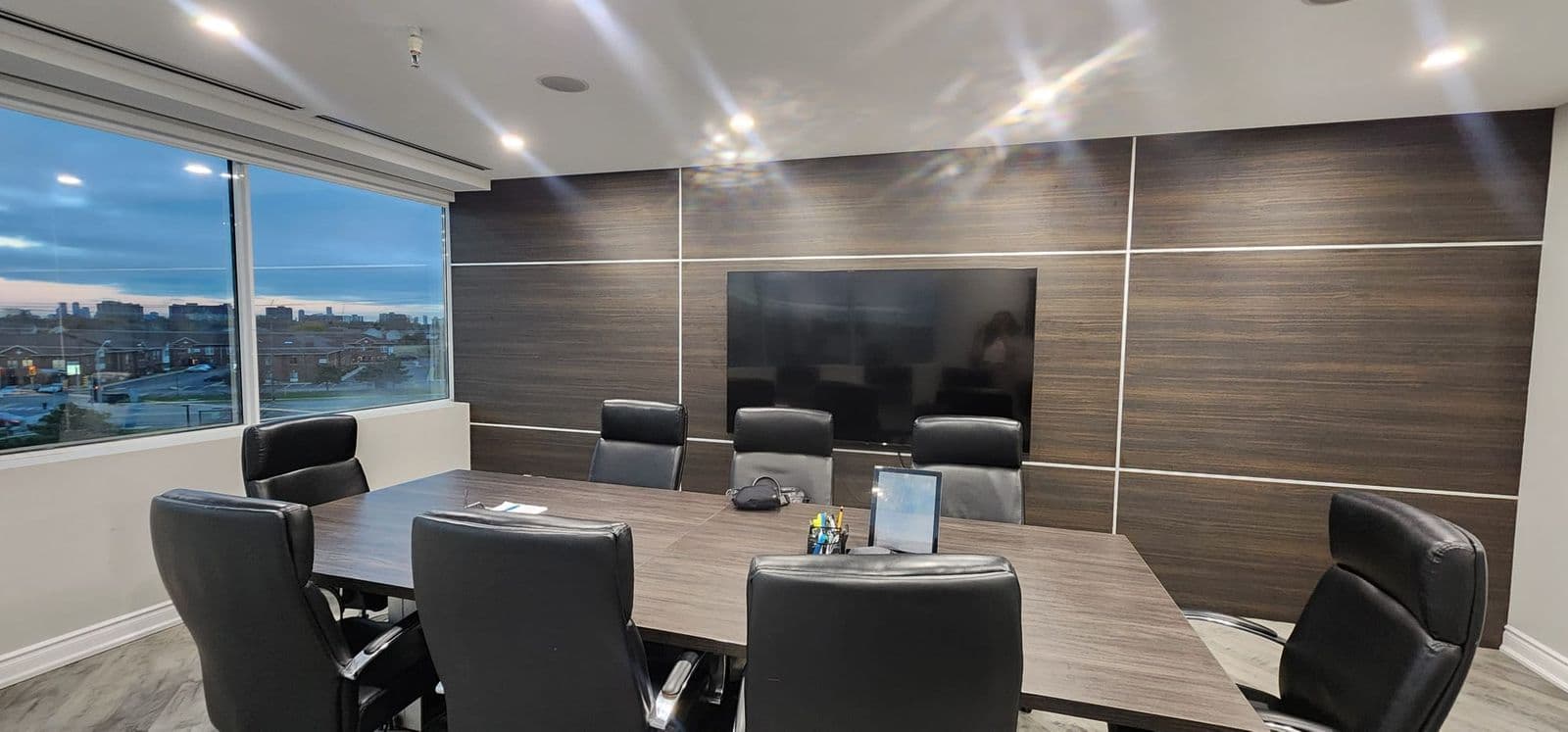 The firm's boardroom, a long table under walnut panelling with windows looking north over Mississauga at dusk.