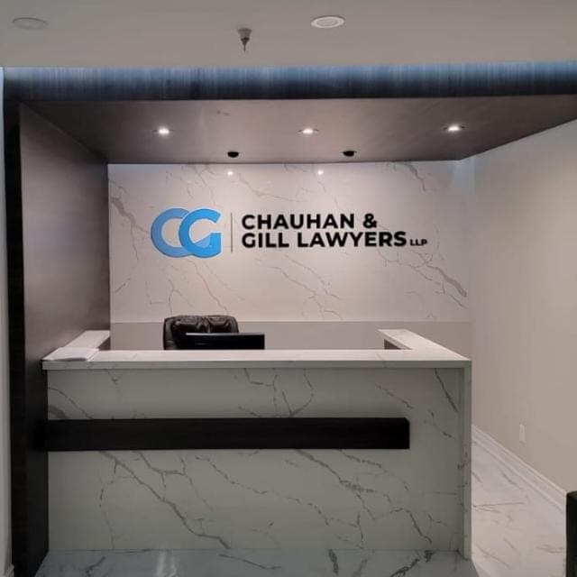 The reception desk at Chauhan & Gill Lawyers, with the firm's mark mounted on a white marble wall.